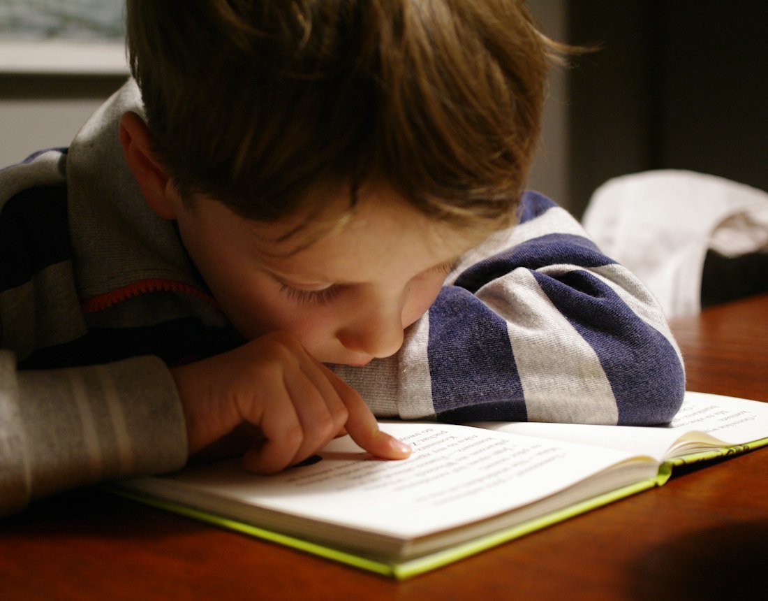 A child reading a book at a wooden table