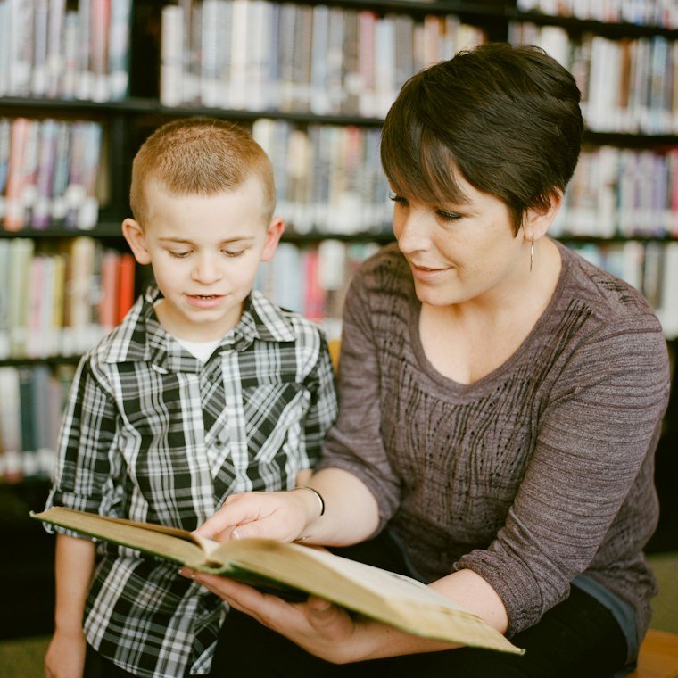 An adult and a child reading a book together