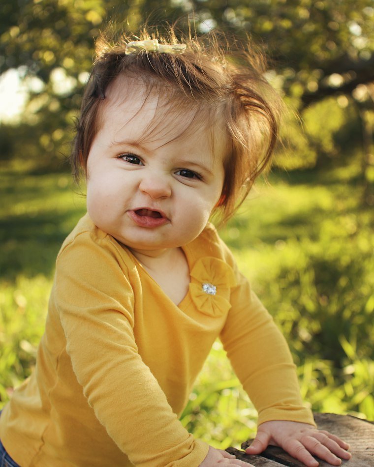 A young child in a yellow top, smiling