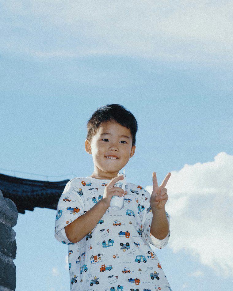 A young child smiling and making a peace sign