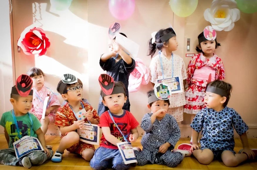 Children in festive outfits and paper headbands sitting together at a class celebration