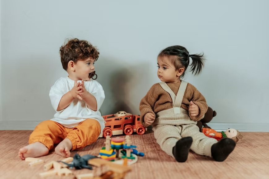 Two toddlers sitting on the floor playing with wooden toys
