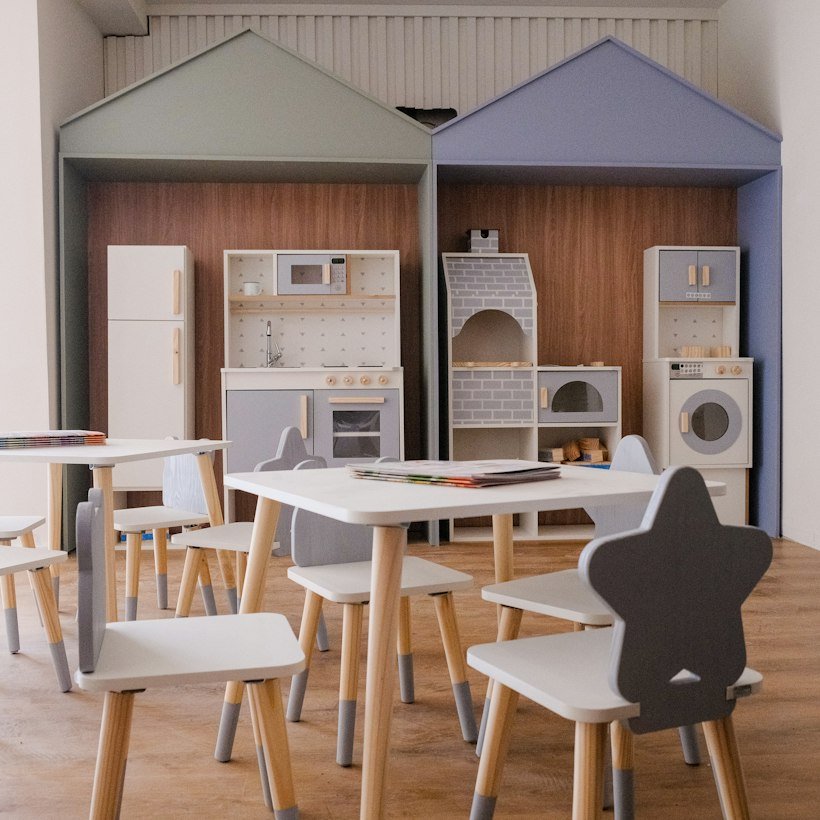 A children's play kitchen area with small tables and chairs