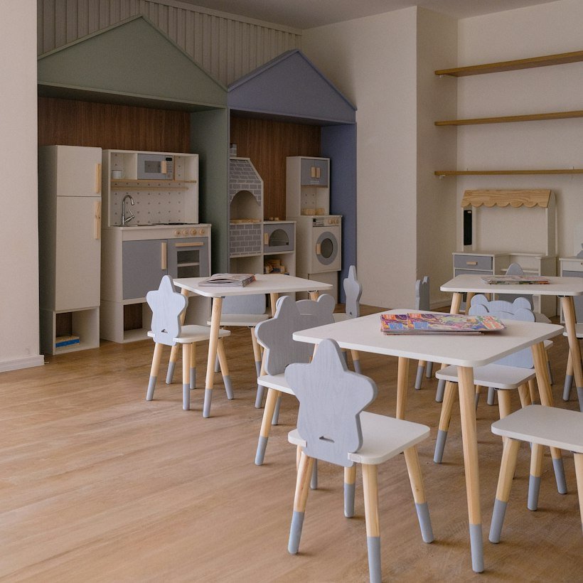 A playroom with small tables, chairs and soft lighting